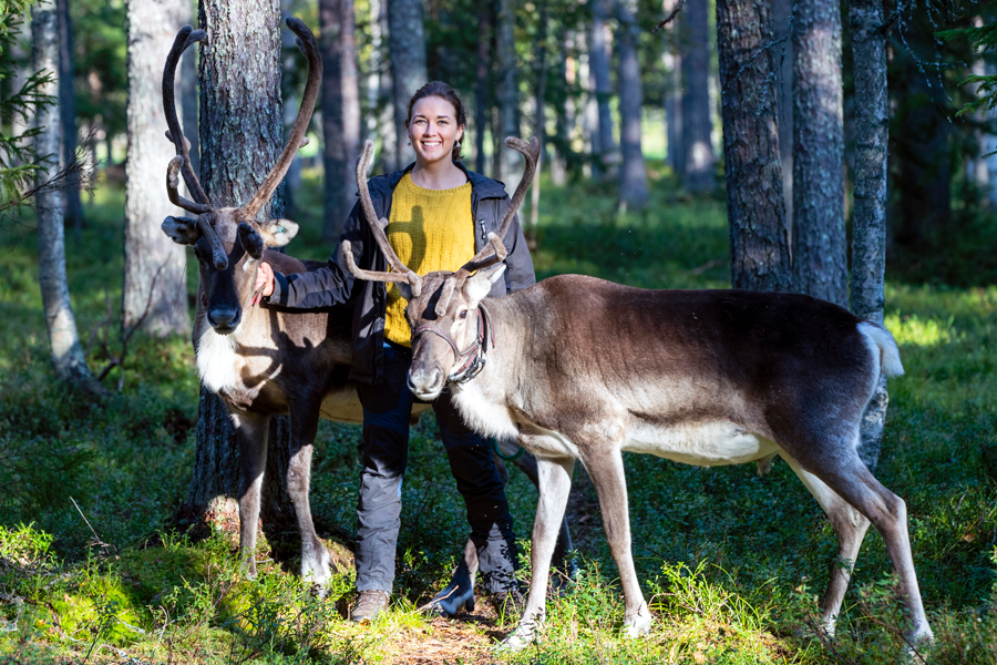 Olga Oinas-Panuma kahden poron kanssa metsässä.